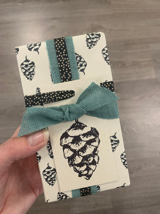 Cadeautje, ingepakt in duurzaam inpakpapier gemaakt van landbouwrestafval | Dennenappel